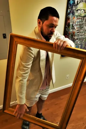 Stow Dunham, founder of Phi Gallery, holding an empty gilded frame.
