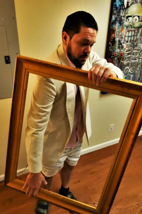 Stow Dunham, founder of Phi Gallery, holding an empty gilded frame.