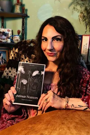 Dana Gillan holding her poetry collection, Intimate Nuances.
